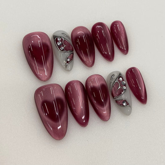 Burgundy Veil nail art flat lay close-up showing handcrafted art detailing on almond nails