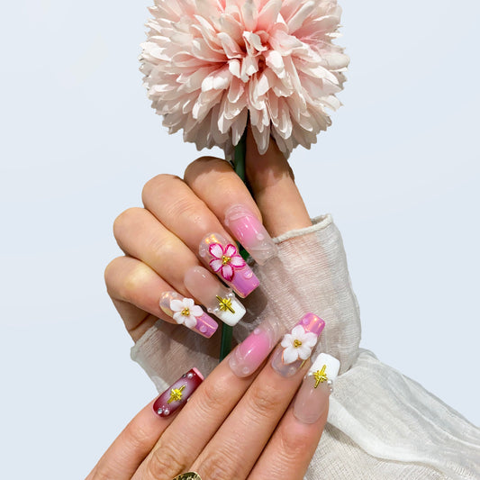 On-hand wear display of Blossom Fairy square nails holding a pink flower prop