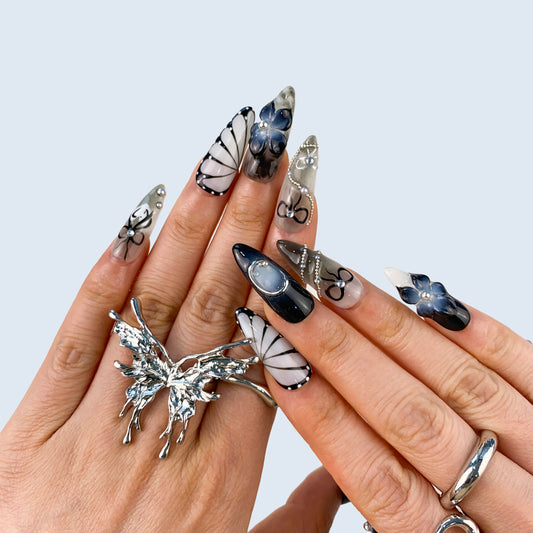 On-hand try-on of Noir Elegance stiletto nails showing gothic floral and silver accents