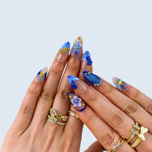On-hand try-on of Moonlit Petals nails showing cobalt blue French tips and stars