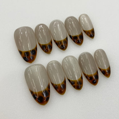 Flat lay photo of Amber French nails showing amber tortie tips and cat-eye glow