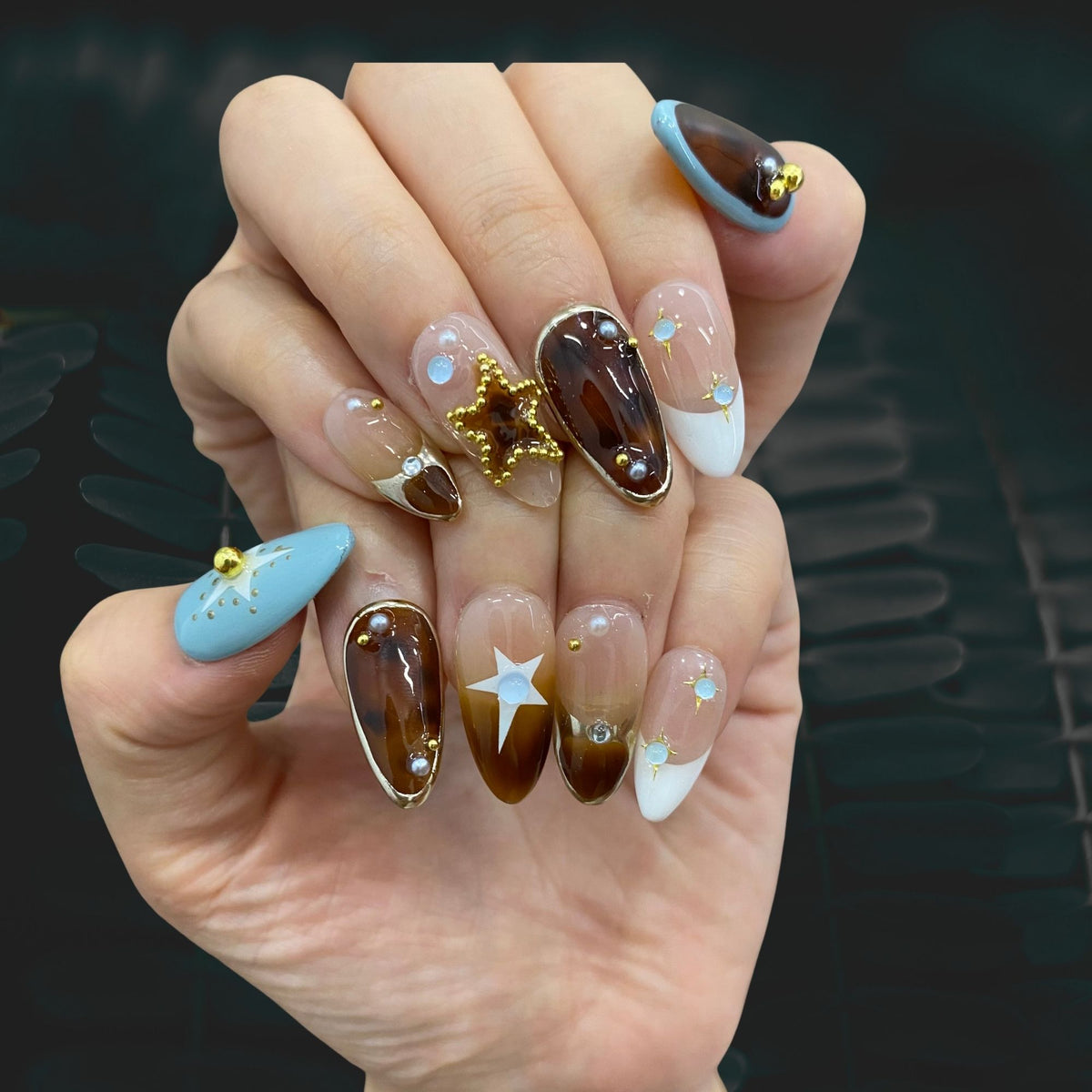 On-hand try-on of Celestial Pearl Ensemble nails showing mocha tortie and starbursts