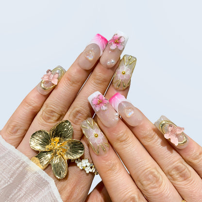 On-hand try-on of Ribbon Dream nails showing 3D pink petals and butterfly charms