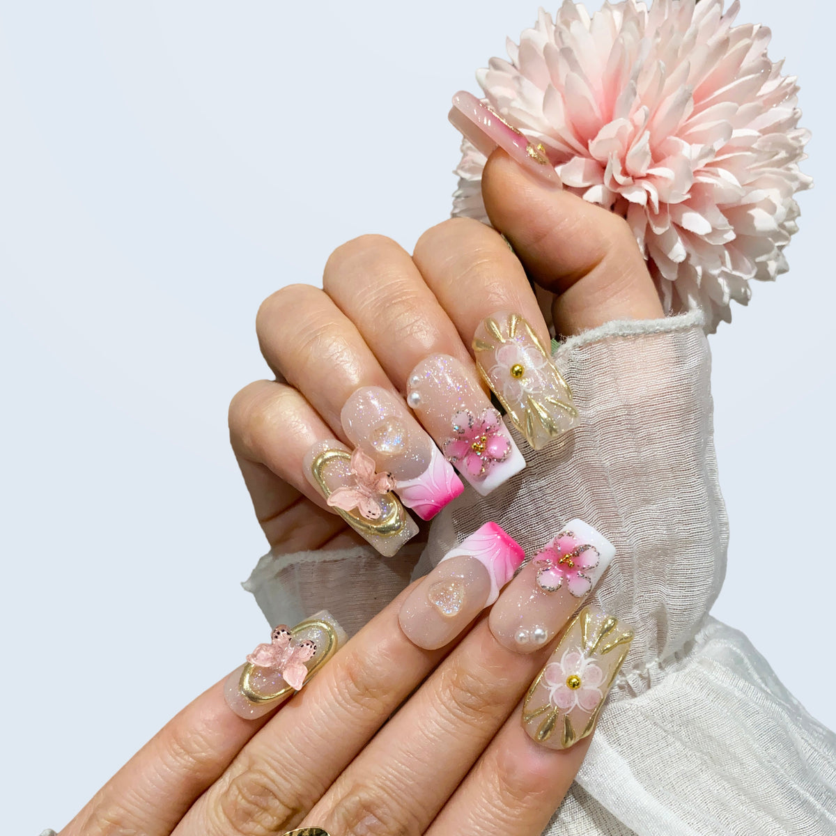 Angled view of Ribbon Dream nails displaying 3D gold bows and pink French tips