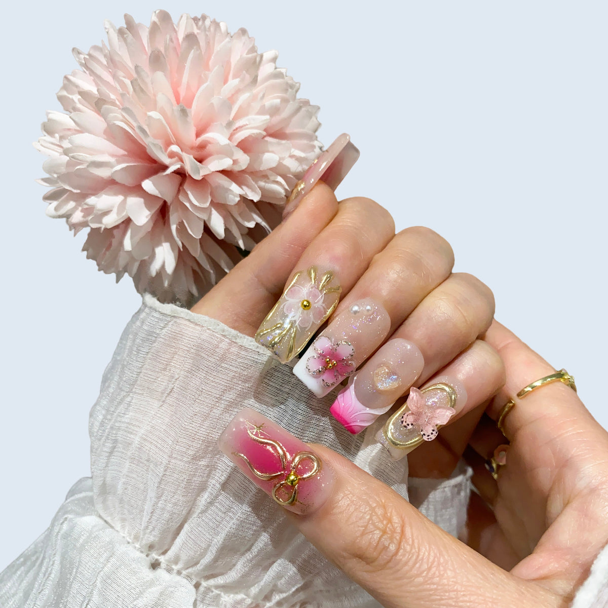 Single hand wearing Ribbon Dream square press-on nails holding a pink flower