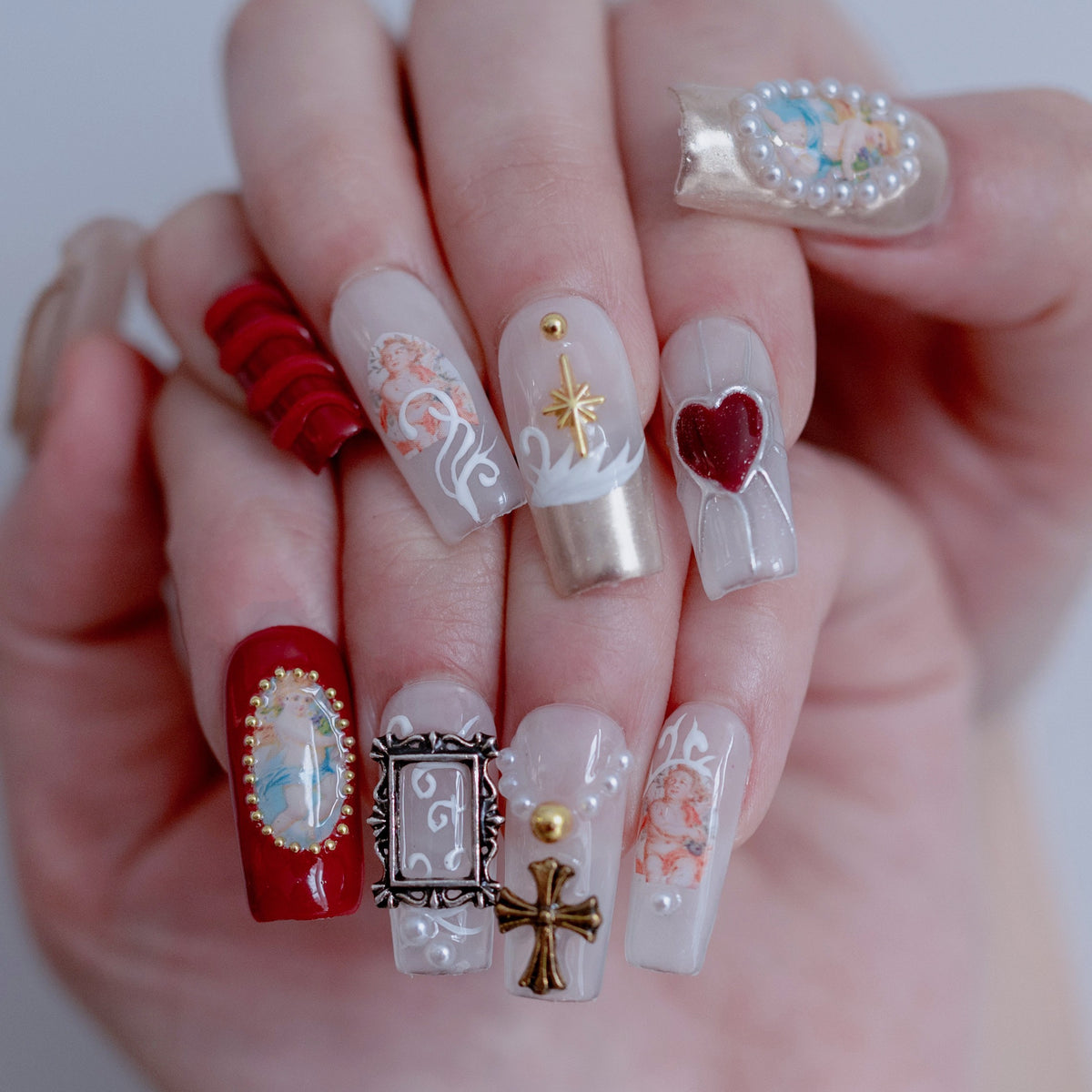 On-hand try-on of Angelic Vintage Glam nails showing 3D gold crosses and cherubs