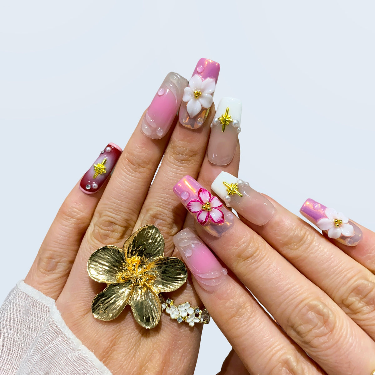Full hand view of Blossom Fairy square nails paired with gold flower ring
