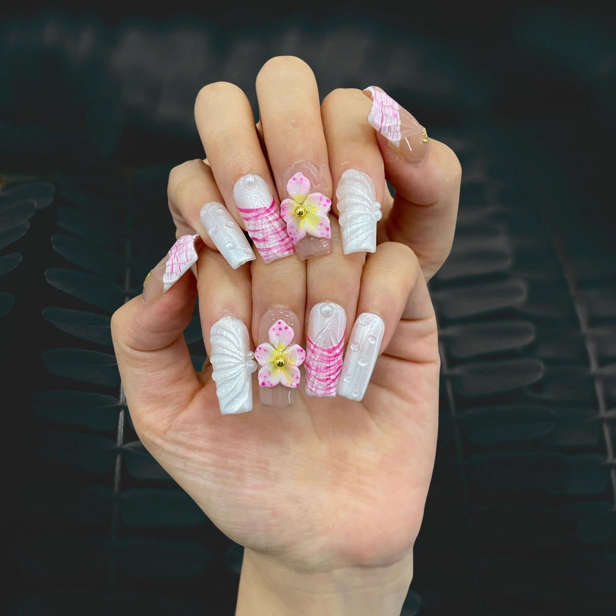 Pearl Wave Delight medium square nails worn on hand in indoor ambient lighting