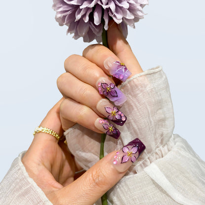 Both hands wearing Midnight Blooms plum ombre square press-on nails in light
