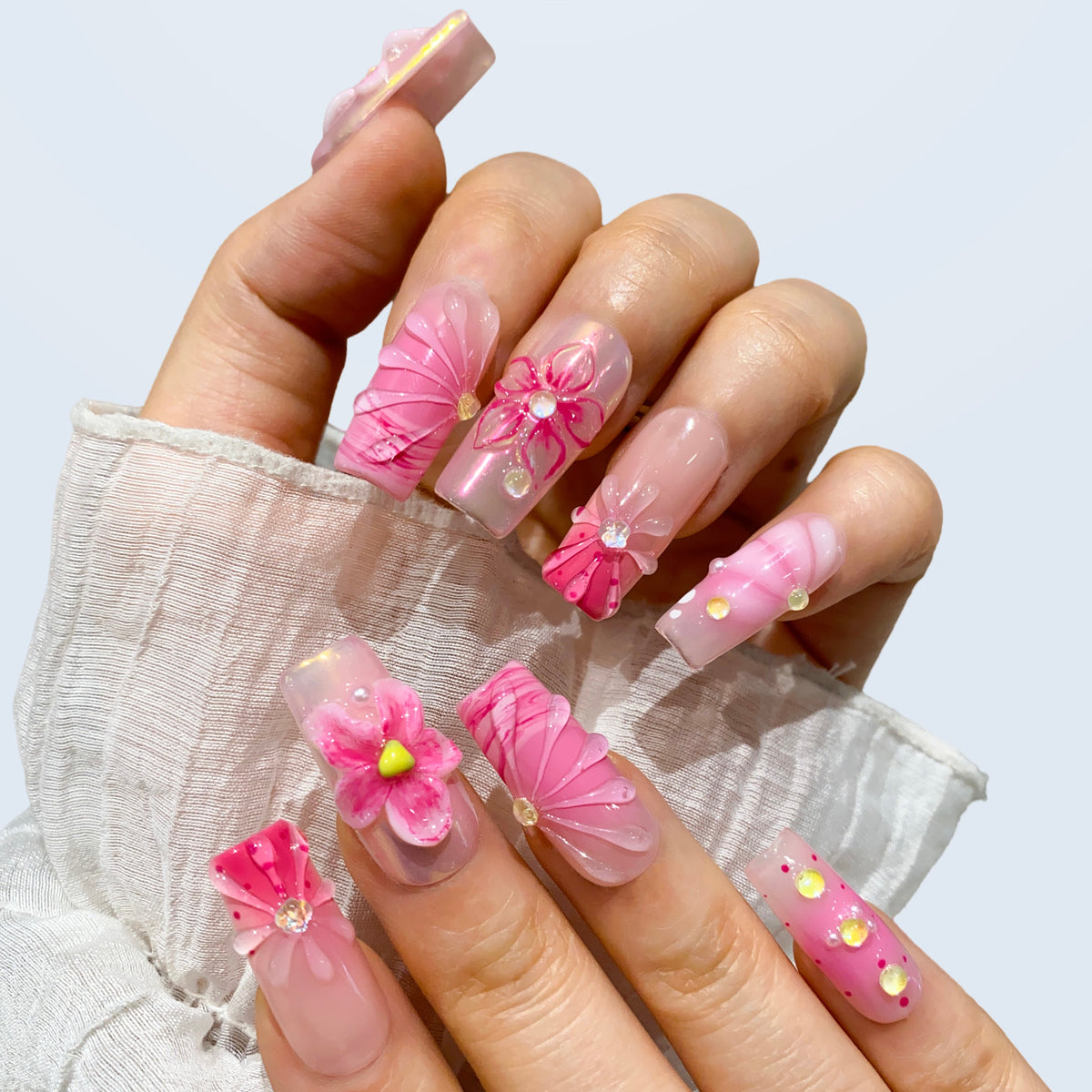 Blush Bloom Spark square nails shown with sheer sleeves and 3D floral charms