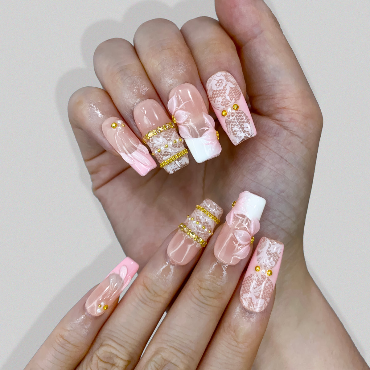 Lifestyle wear photo of Blush Lace nails highlighting gold beaded bangles and pearls