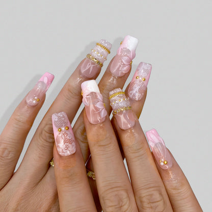 Angled view of Blush Lace press-on nails displaying pink French tips and gold accents