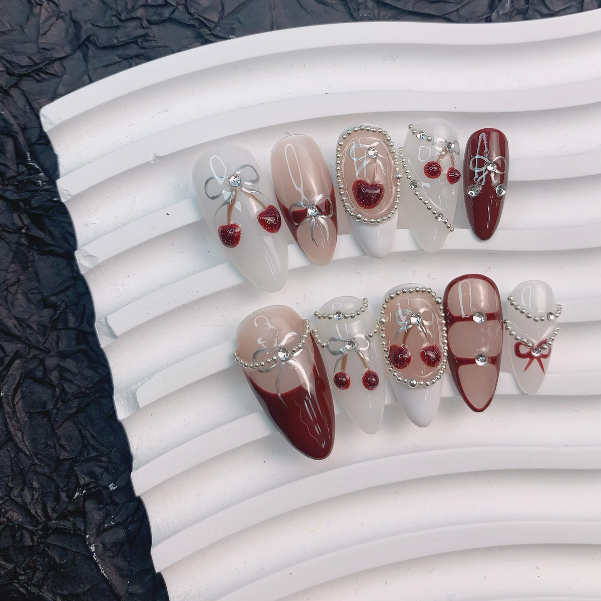 Cherry Bow nail art on flat surface close-up showing 3D ribbon bows on almond nails