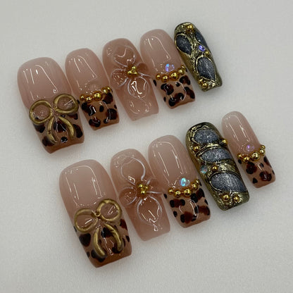 Flat lay photo of Golden Muse nails showing 3D gold bow and beaded French rims