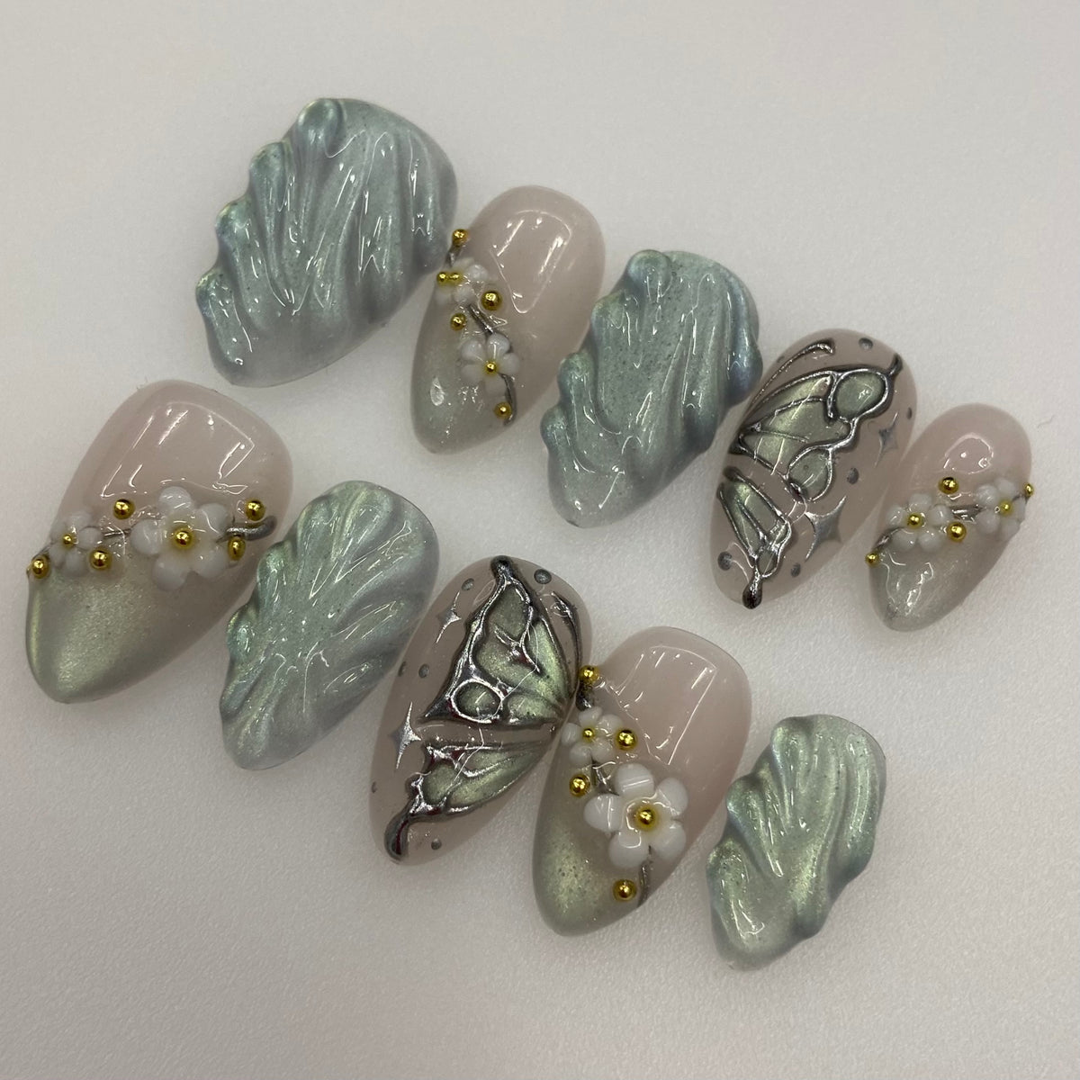 Full 10-piece set of sage green cat-eye press-on nails with white floral accents