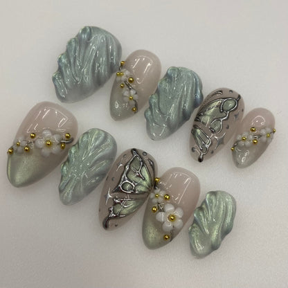 Full 10-piece set of sage green cat-eye press-on nails with white floral accents
