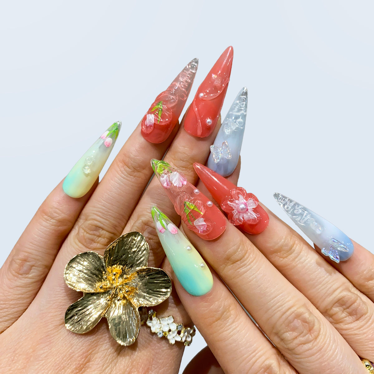 Blush Bloom stiletto nails styled with a gold statement flower ring on hand