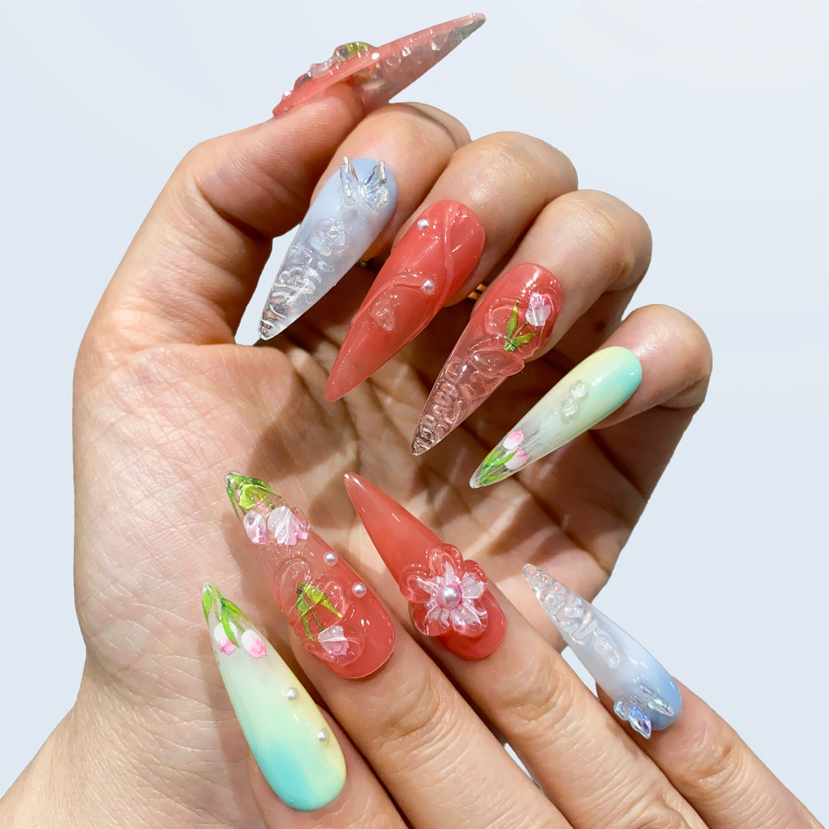 Both hands wearing Blush Bloom rose and blue gradient nails in soft light