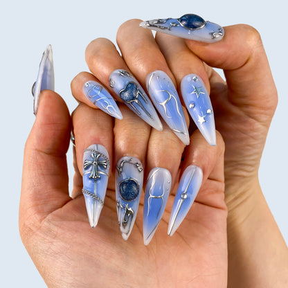 Misty Hymn nail art close-up showing sapphire cat eye gem and chain-wrapped silver cross