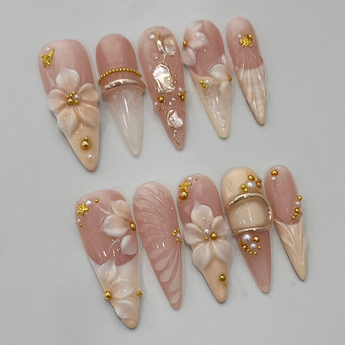 Angled view of Ethereal Shell nails showing 3D sculpted blossoms and gold wire wraps