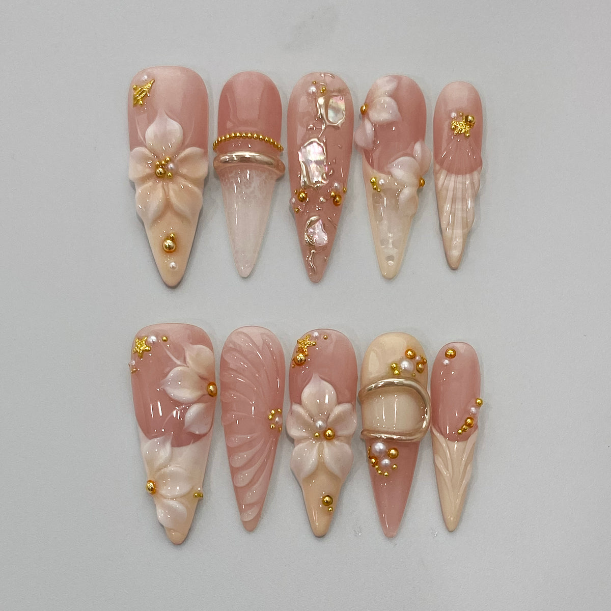 Full 10-piece flat lay display of Ethereal Shell pearlescent stiletto press-on nails