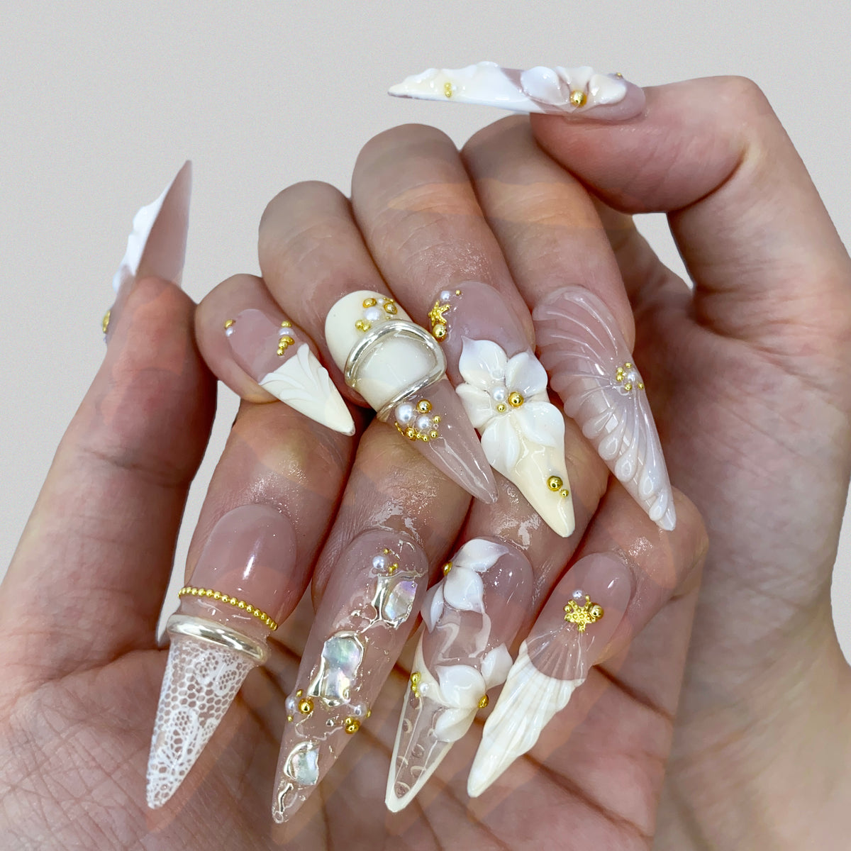 On-hand try-on of Ethereal Shell stiletto press-on nails showing 3D floral art