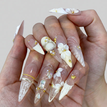 On-hand try-on of Ethereal Shell stiletto press-on nails showing 3D floral art
