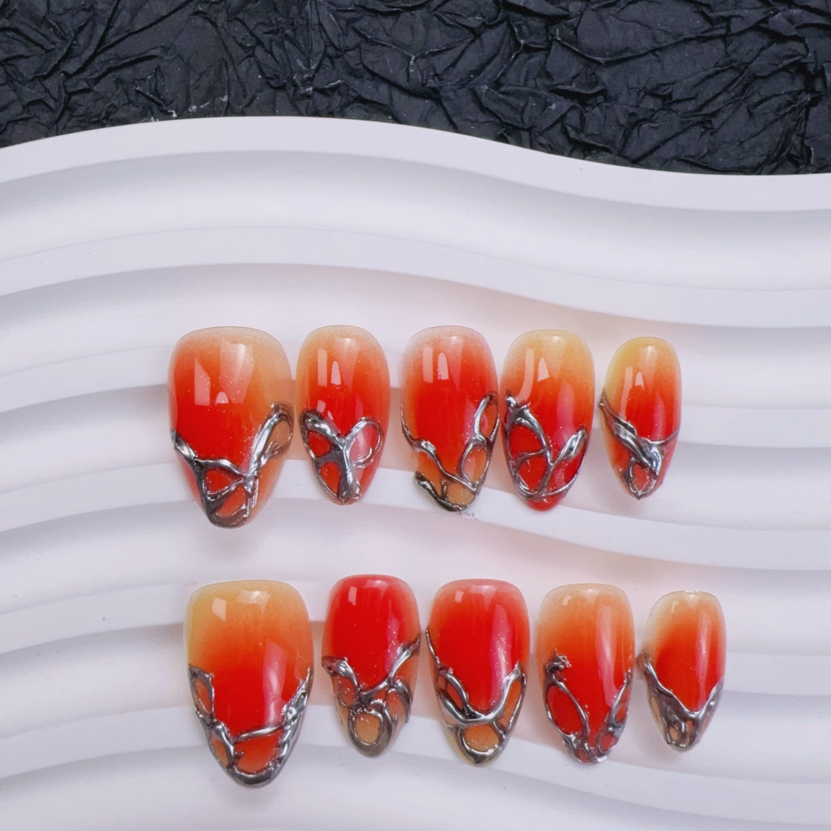 Sunset Chrome almond press-on nails with 3D molten silver frames and red aura ombre