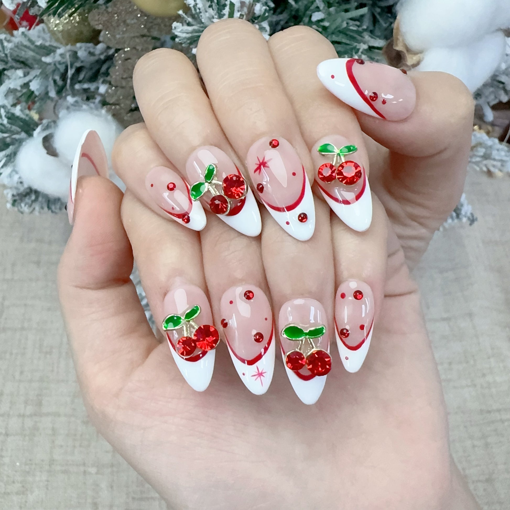 Both hands wearing Velvet Cherry French nails in cozy holiday tree lighting