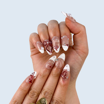 Full set wear display of Ribbon Bliss white French and red bow press-on nails