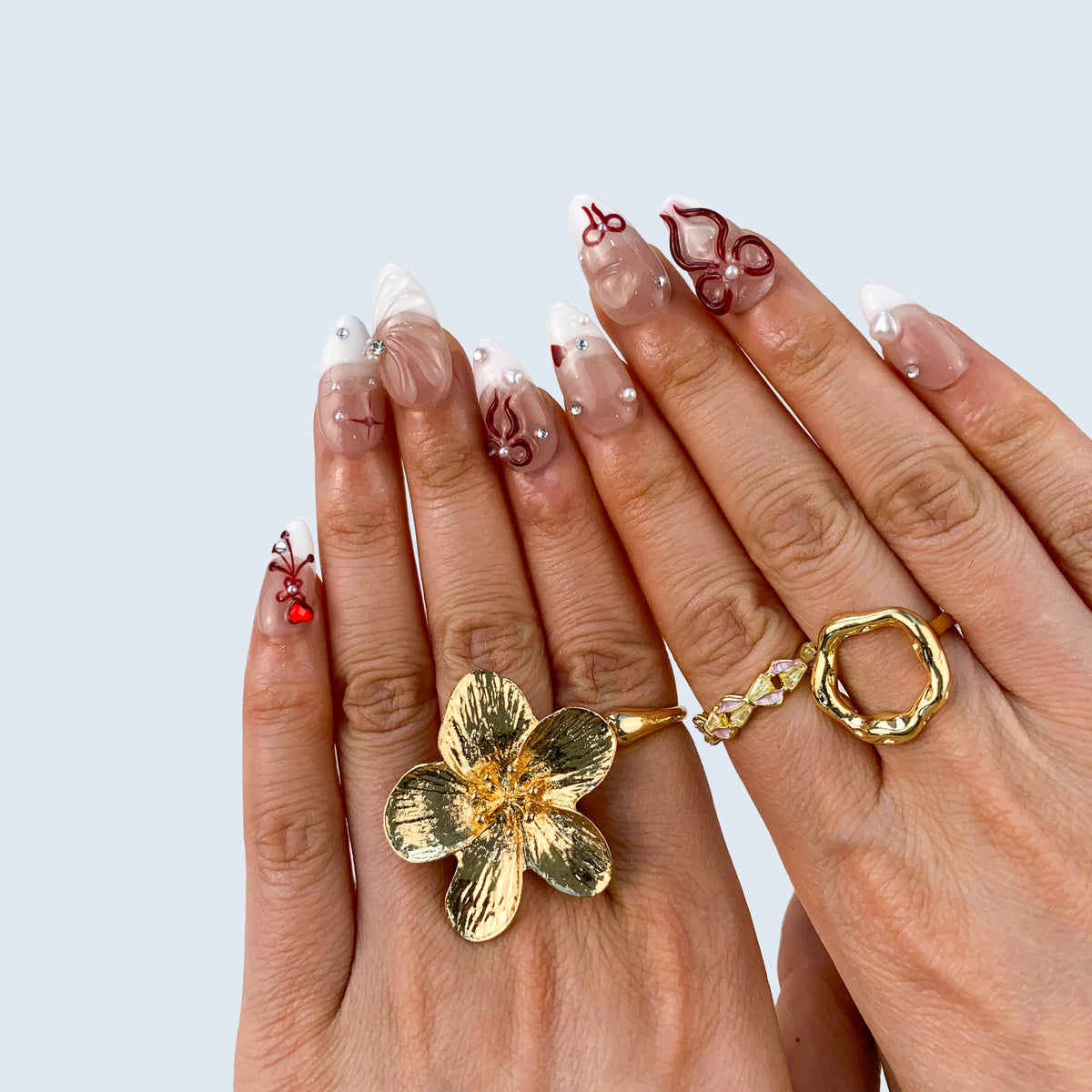 Angled view of Ribbon Bliss almond nails displaying 3D pearl hearts and bows