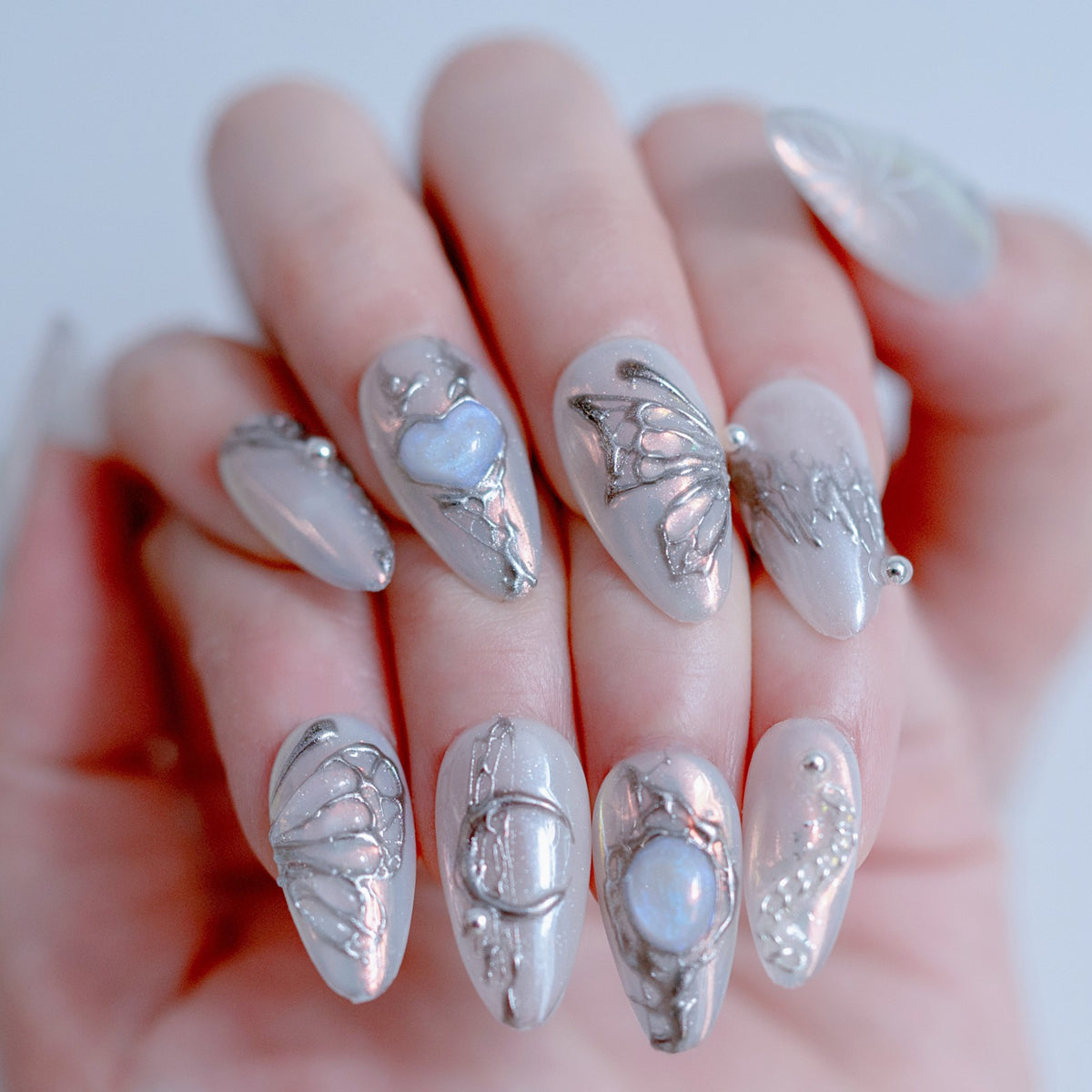 Single hand wearing Gossamer Butterfly iridescent chrome almond press-on nails
