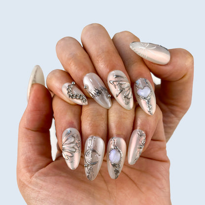On-hand try-on of Gossamer Butterfly nails showing molten silver wing art and pearls