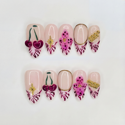 Flat lay photo of Royal Petals nails displaying 3D wine cherries and gold stars