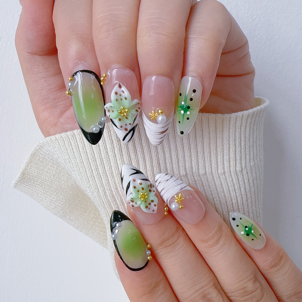 Both hands wearing Mint Floral Whisper botanical almond press-on nails in light