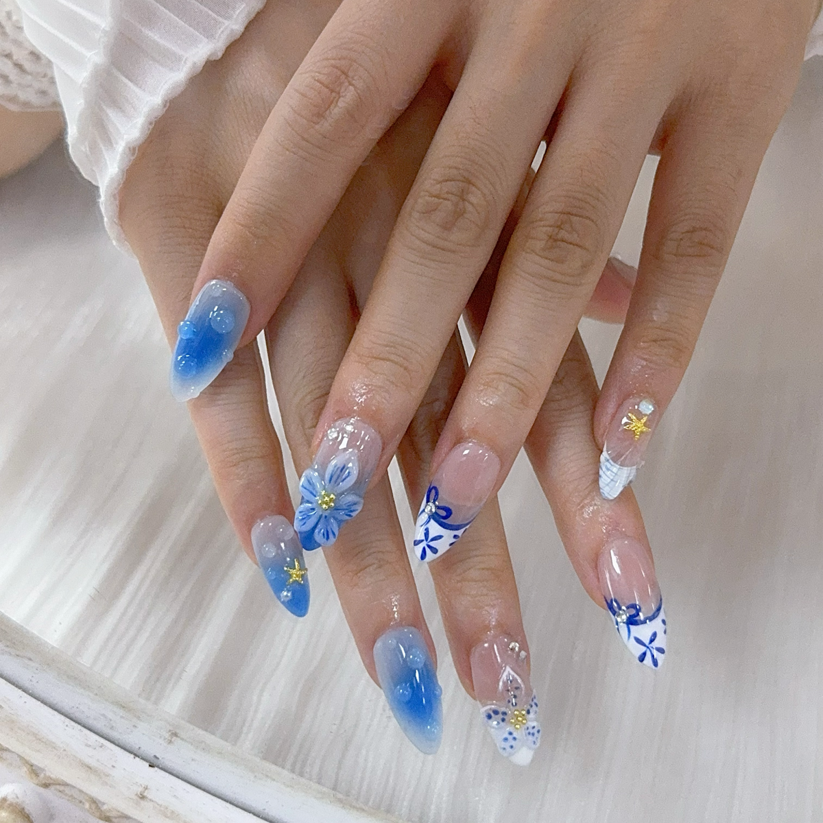 Full set wear display of Oceanic Mirage coastal blue French nails on mirror table