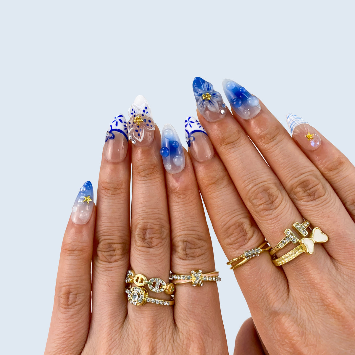 Both hands wearing Oceanic Mirage blue porcelain French press-on nails in sunlight