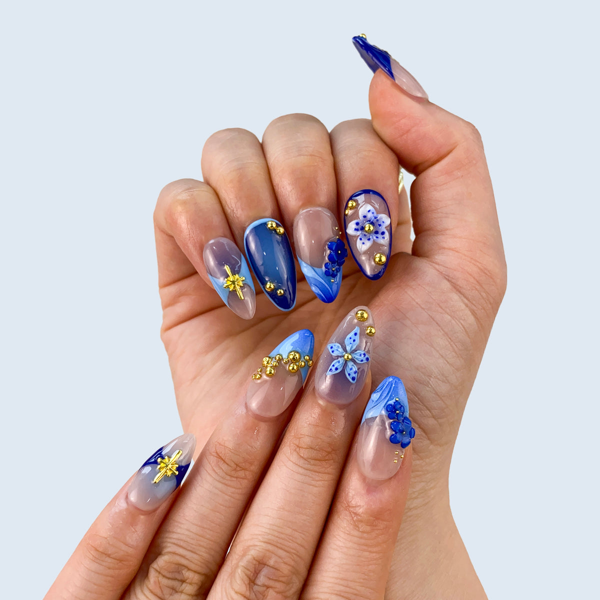 Both hands wearing Moonlit Petals blue floral press-on nails in natural light