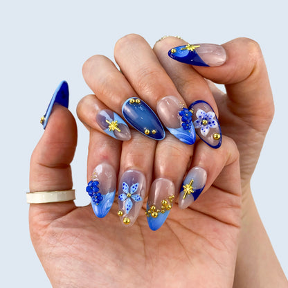 Close-up view of Moonlit Petals nails highlighting 3D blue petals and gold stars