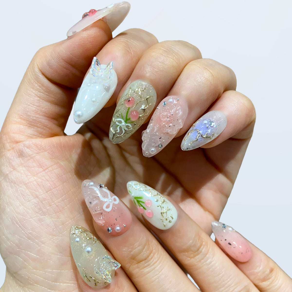 Both hands wearing Fairy Secrets pastel botanical press-on nails in soft light