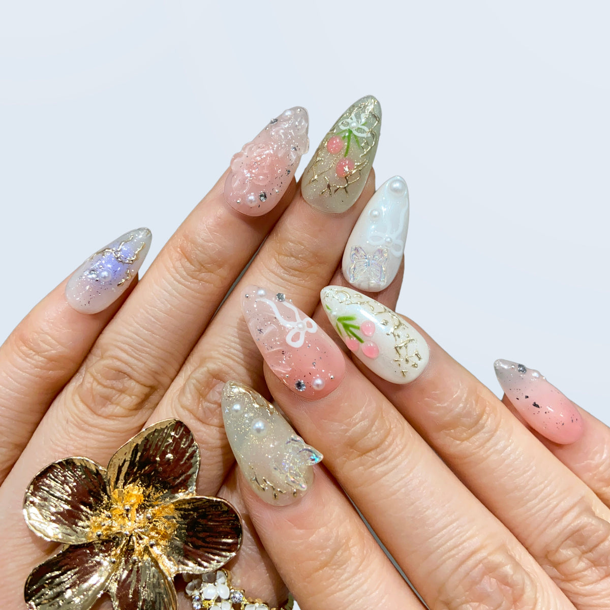 Fairy Secrets floral almond nails styled with a gold statement flower ring