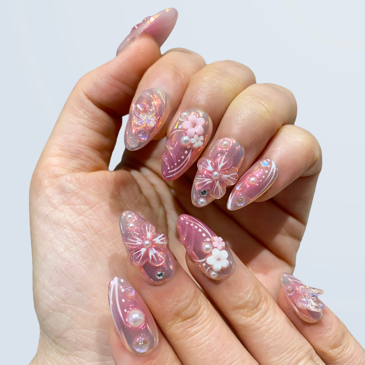 Single hand view of Luminous Dream medium almond nails with pearlescent accents