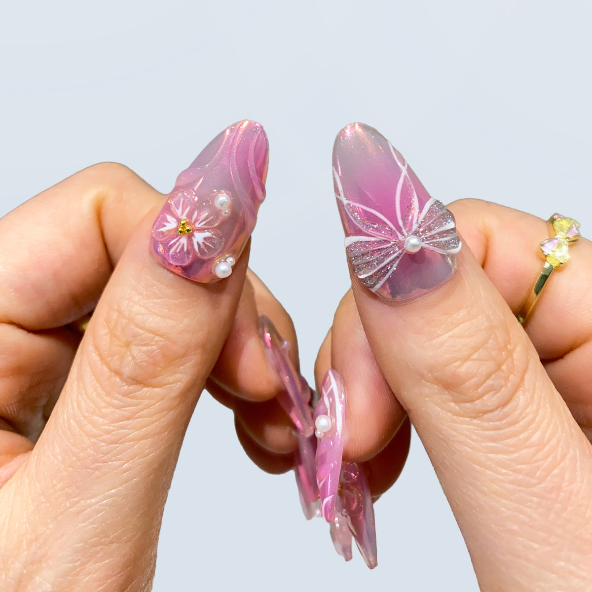 Side view of Fairy Glaze nails showing intricate 3D string bow and pearl core