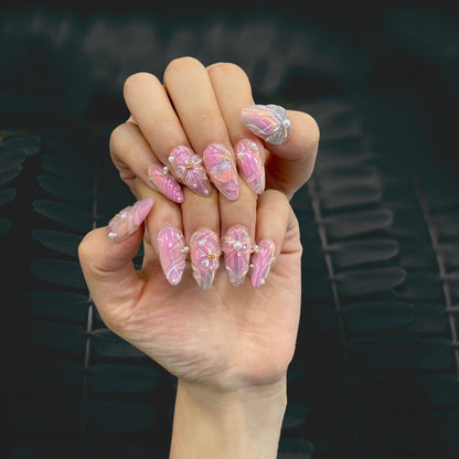 Elegant manicure display of Fairy Glaze pink almond nails on dark background