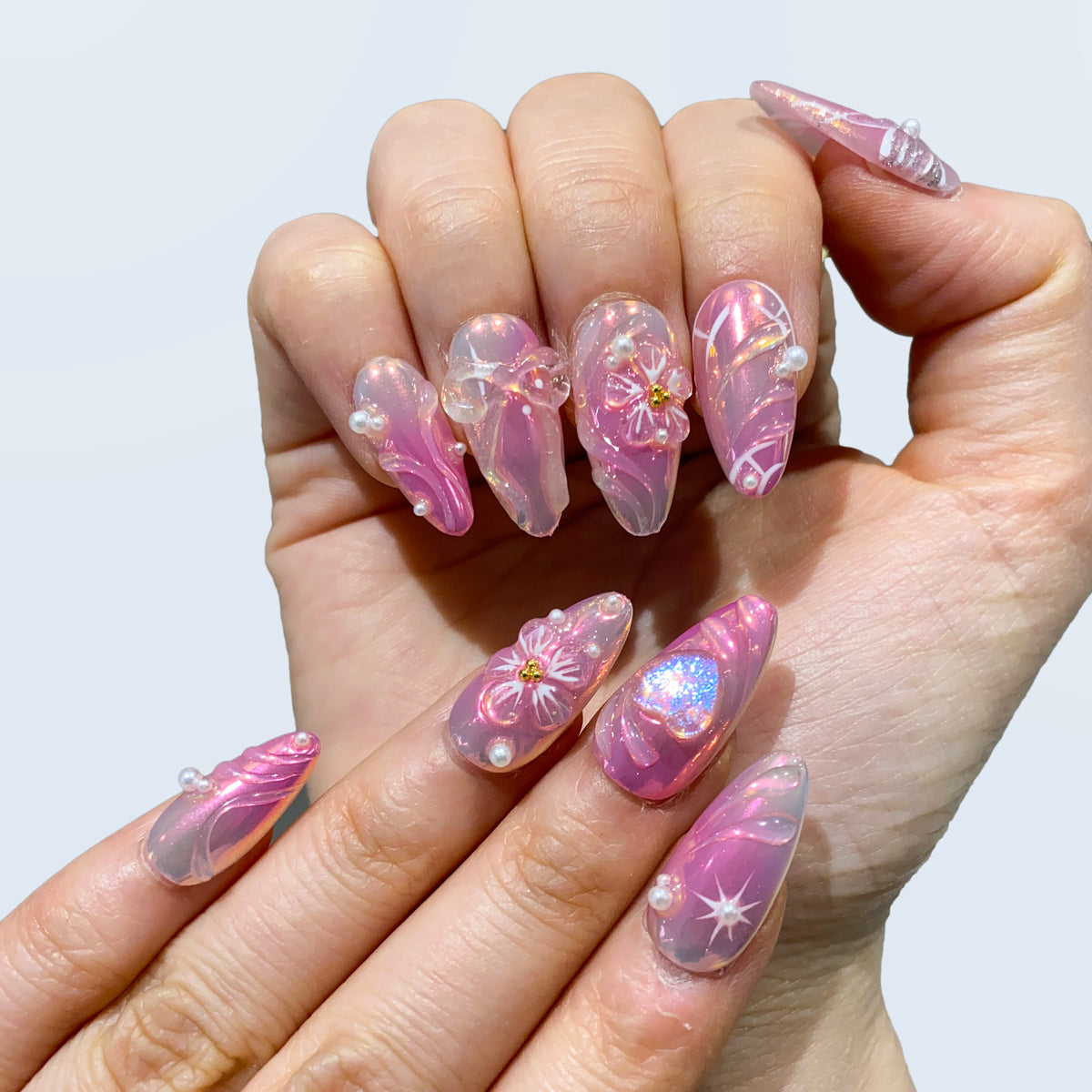 Full hand display of Fairy Glaze nails displaying pink aura gel and pearls