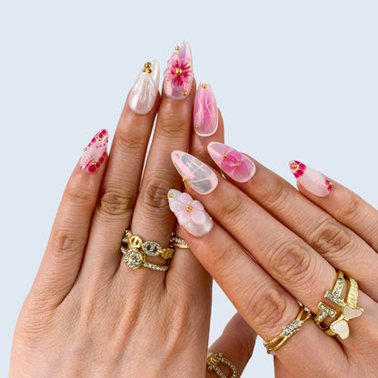 Full hand display of Petal Pop almond press-on nails showing raised 3D pink floral charms