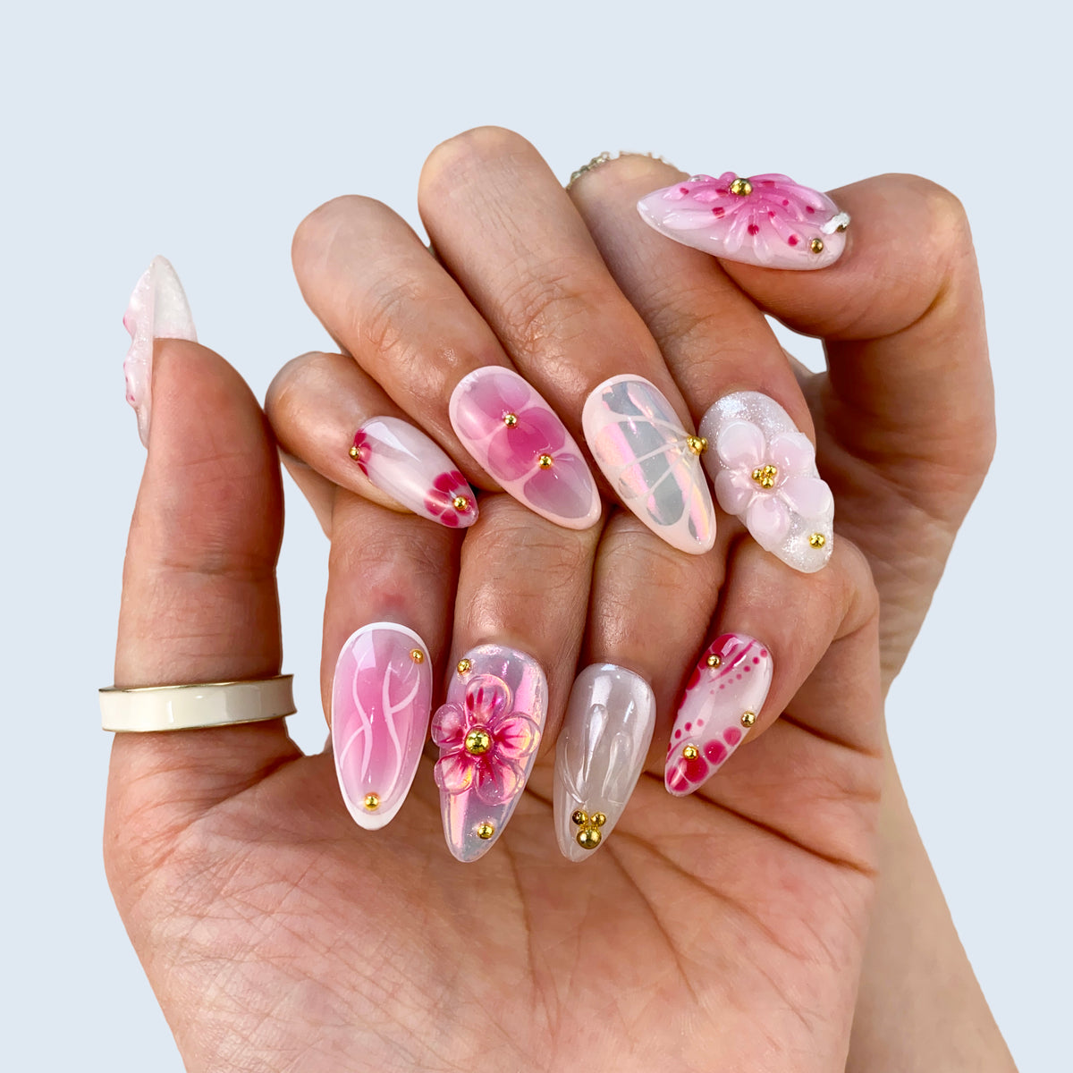 Clasped hands wear display of Petal Pop nails showcasing glossy shine and 3D floral crafts