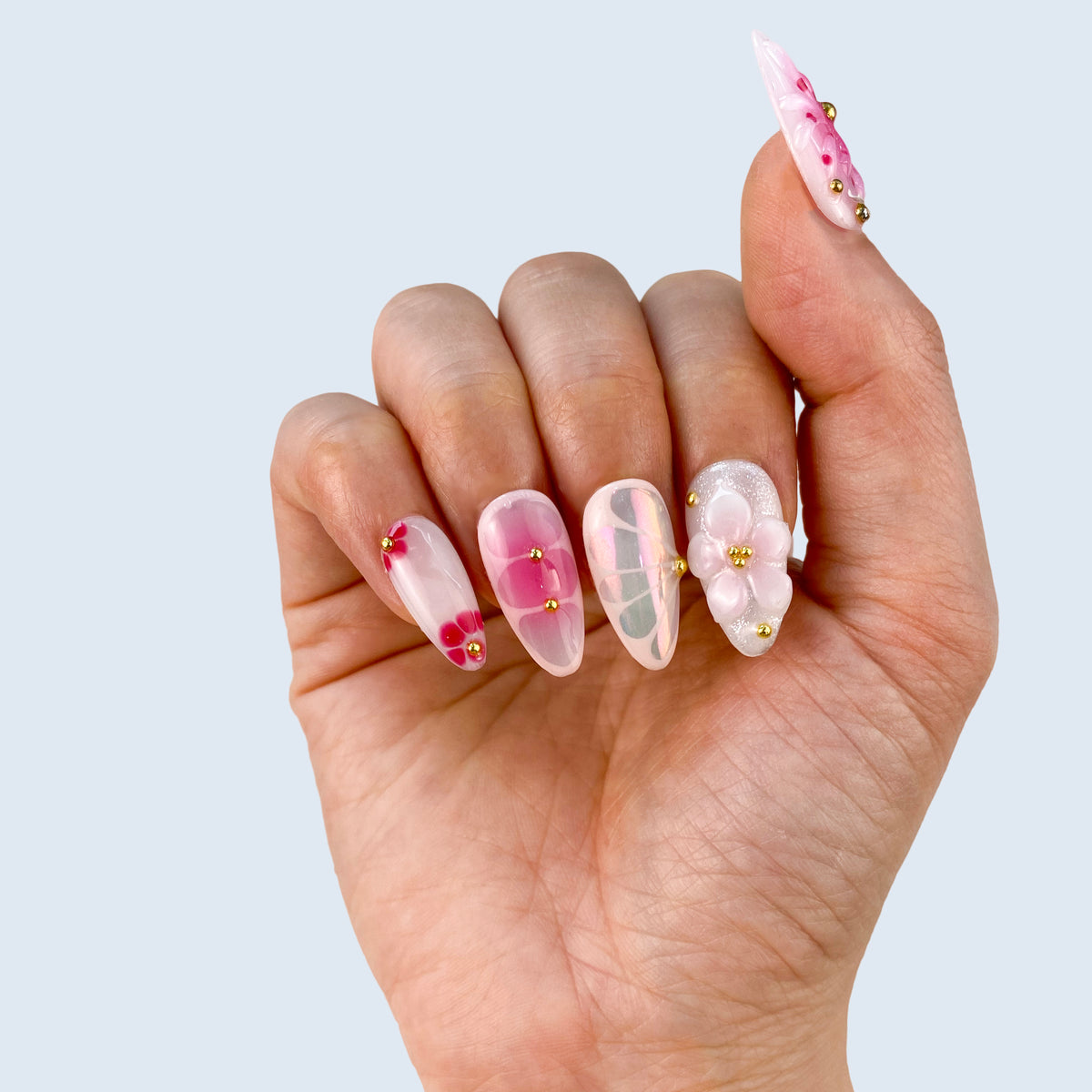 Single hand view of Petal Pop medium almond nails with pink aura accents and glossy finish