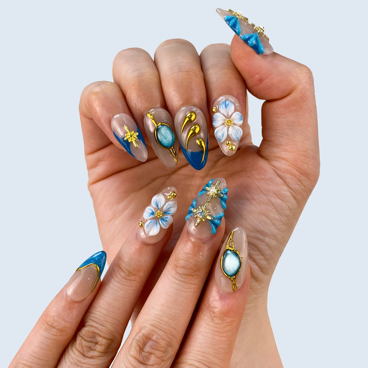 Single hand view of Celestial Shore medium almond nails with raised gold accents