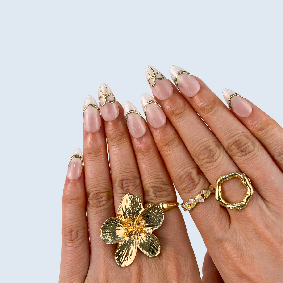 Angled view of Gilded Pearl Bow almond nails displaying clean girl French tips